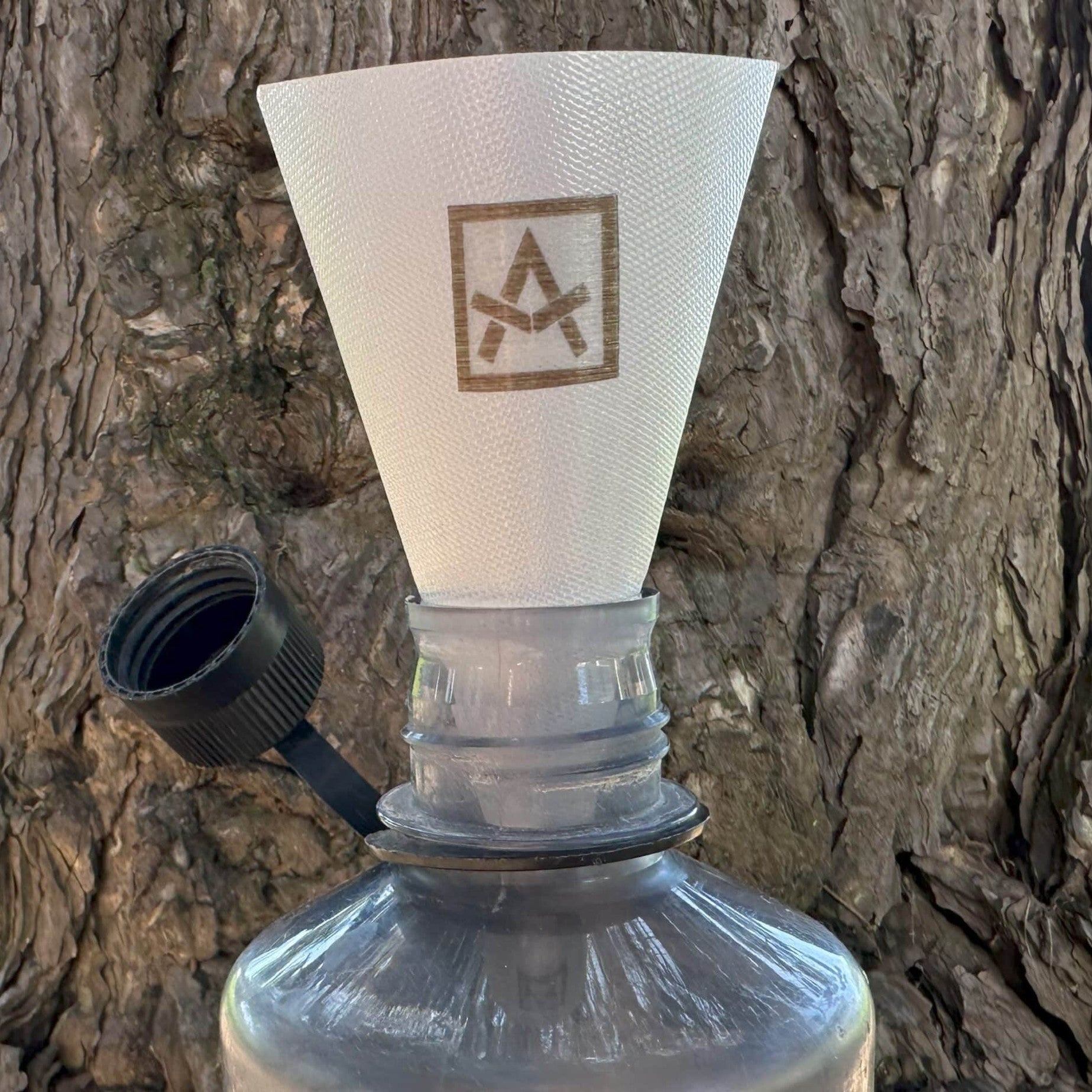 Ultralight Fold-flat Funnel Adotec Gear ultralight camping funnel placed on a water bottle for easy pouring.