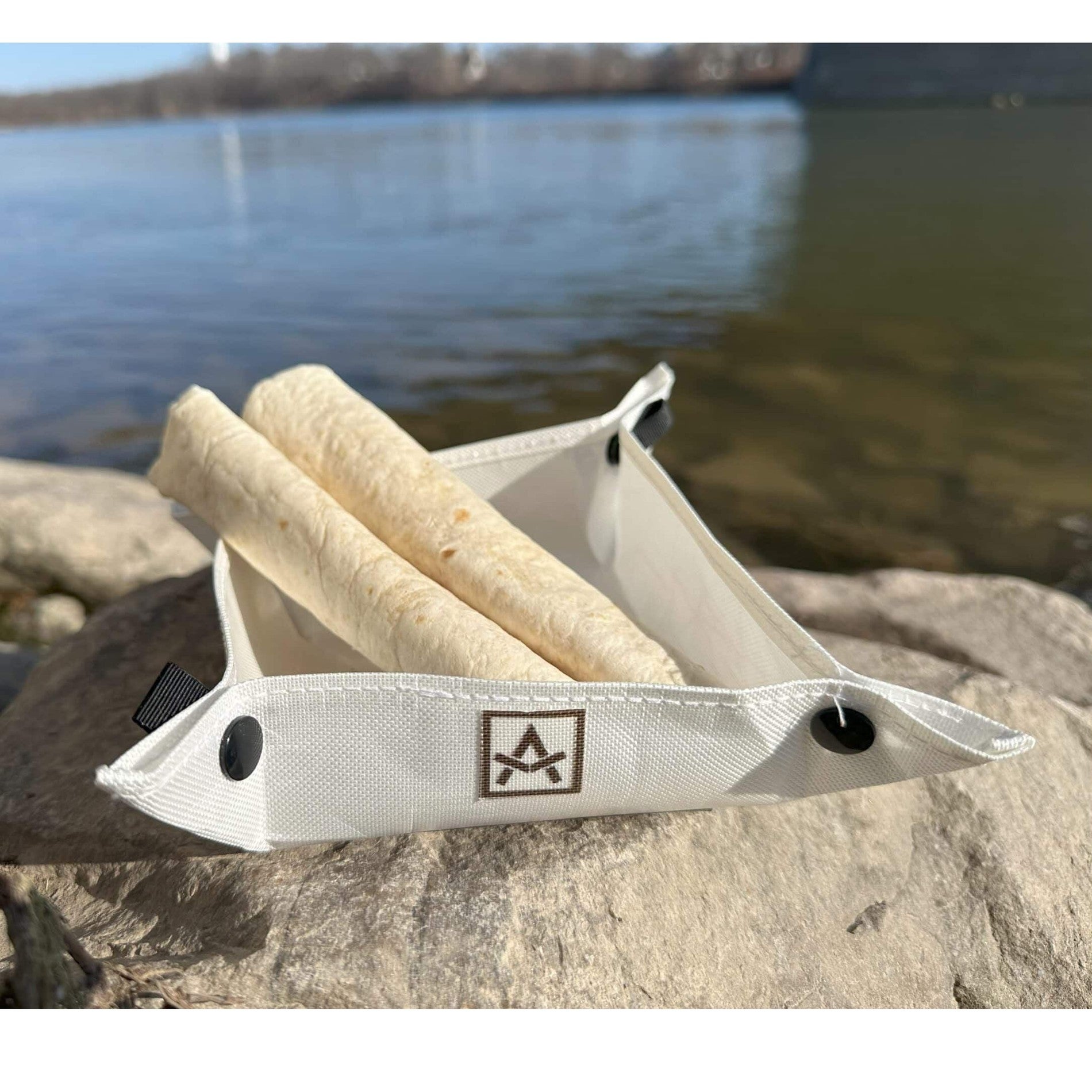 Ultralight Camp Bowl Adotec Gear Ultralight Camping Bowl with rolled tortillas on rocky shoreline near water