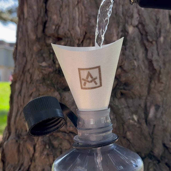 Adotec Gear ultralight camping funnel pouring water into a bottle outdoors