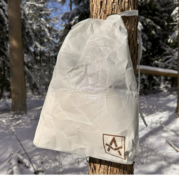 Adotec Gear bear-resistant food bag hanging on a tree in a snowy forest environment